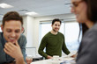 © Mint Images - Three people in a large open plan office, two in the fore.