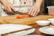 © akeeris - an Asian woman chef preparing salmon piece with sharp knife