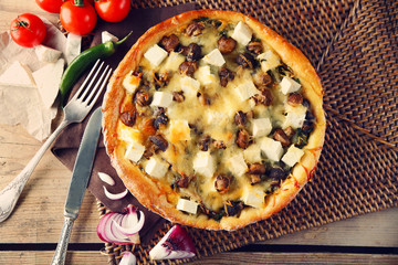 Cheese pie with mushrooms, herbs and sour creme, on wicker mat, on wooden table background