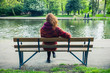 © LoloStock - Woman sittng on bench by a pond in the park