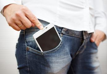 woman pushing big mobile phone in jeans pocket