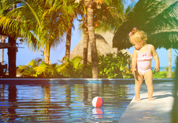 Wall Mural - cute toddler girl playing with ball in swimming pool