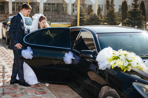 Photographie Bride and groom kissing in limousine on wedding-day.