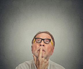 Senior man with glasses looking up isolated gray background