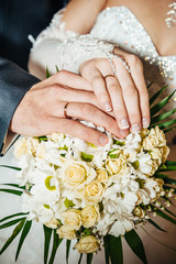 Wall Mural - Hands with wedding rings on bridal bouquet of flowers