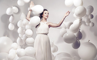 Adorable young woman holding many balloons