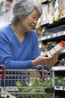© Noel Hendrickson/Blend Images - Senior Asian woman reading label at grocery store