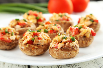 Stuffed mushrooms on plate on white wooden background