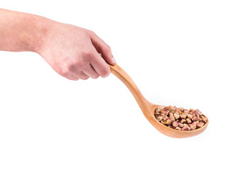 Wooden spoon with pistachios in hand.