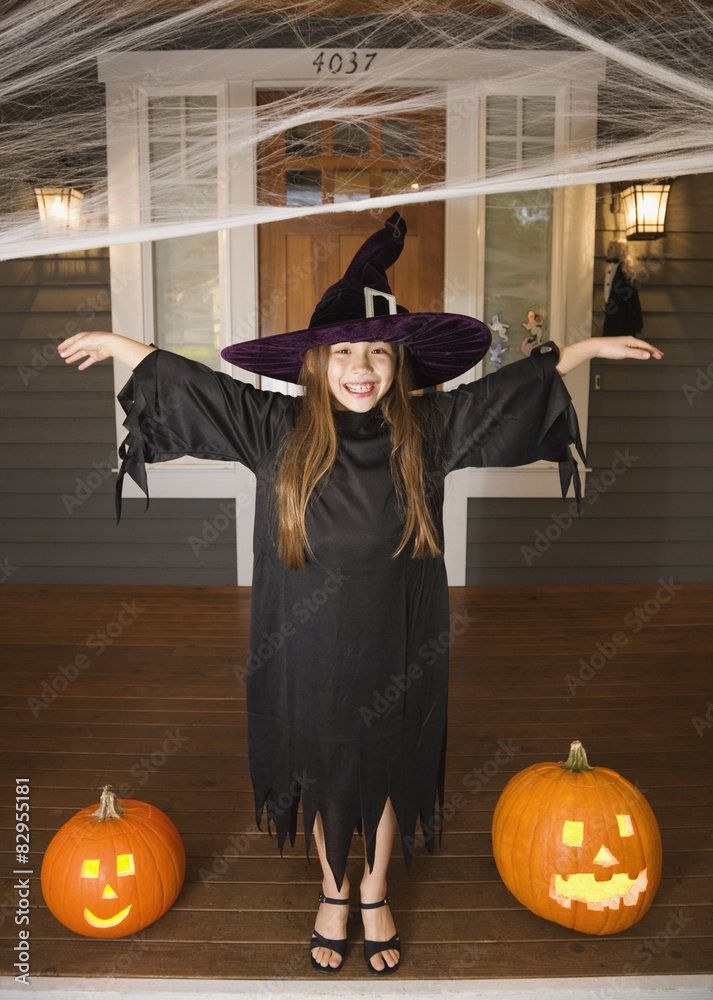 Mixed race young girl in witch costume with Halloween pumpkins Stock ...