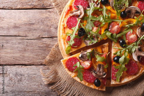 Fototapeta na wymiar pizza with herbs, salami and vegetables horizontal top view
