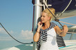 Schöne junge blonde Frau am Meer mit Segelboot