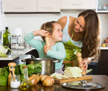 Woman With Little Girl Cooking At Home
