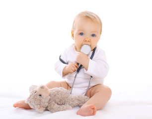portrait of baby playing with stethoscope and teddy bear