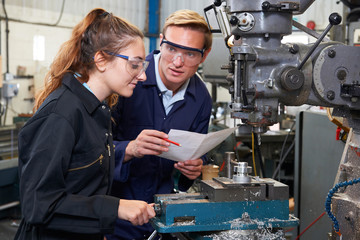 Wall Mural - Engineer Showing Apprentice How to Use Drill In Factory