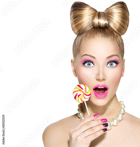 Naklejka dekoracyjna Funny girl with bow hairstyle eating colorful lollipop