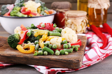 Canvas Print - Frozen vegetables on cutting board, on napkin, on wooden table background