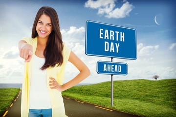 Poster - Composite image of happy casual woman pointing to camera