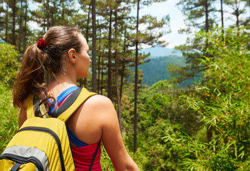 Wall Mural - Woman tourist with a backpack standing on top of the mountain