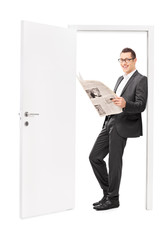 Poster - Businessman reading a newspaper and leaning on door