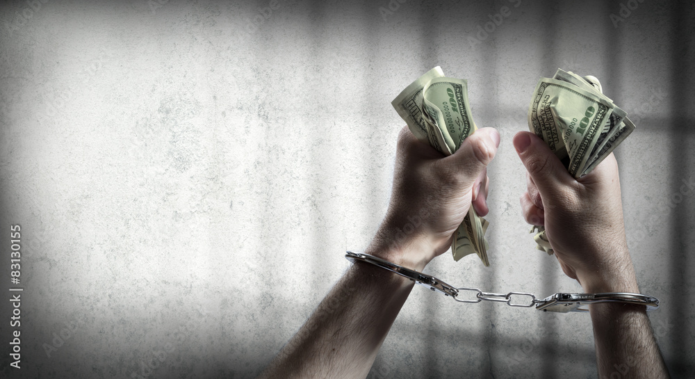 человек в наручниках на фоне пачек денег и документов
