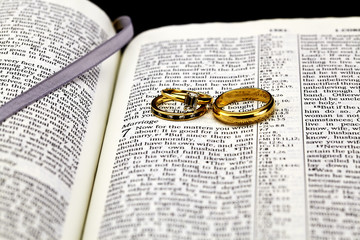 Detailed closeup of gold wedding rings on marriage on open Bible