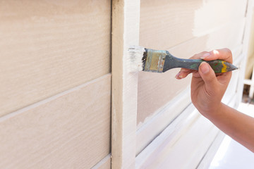 Wall Mural - hand worker holding brush painting white on wood fence