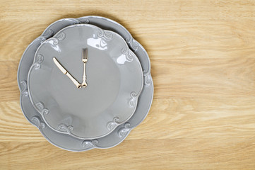 Grey plate clock on a wooden background