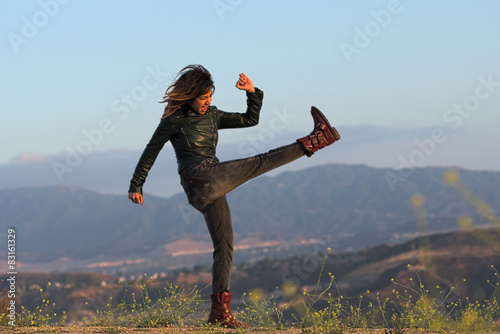 Fotografie, Obraz Woman in leather jacket and boots kicking air