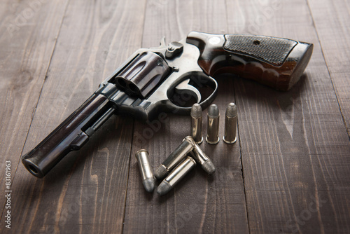 Fotografía black revolver gun with bullets isolated on wooden background