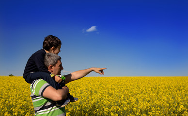 Child on the shoulders of his father in rapseed plantation, 