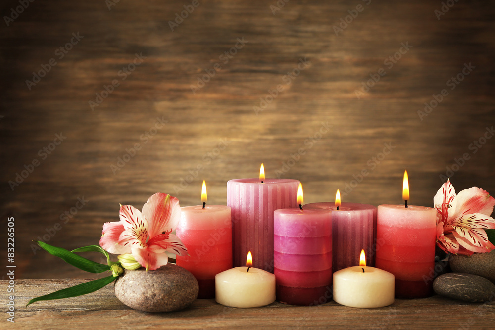 Candles with flowers on wooden background