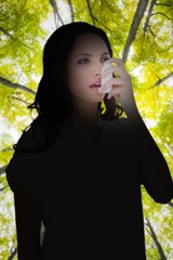 Poster - Composite image of asthmatic brunette using her inhaler 