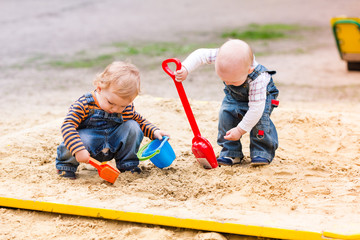 Two baby boys playing with sand