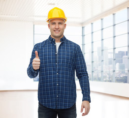 Wall Mural - smiling male builder in helmet showing thumbs up