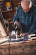 © Zoran Zeremski - Senior carpenter cutting wooden plank with circular saw in his workshop.