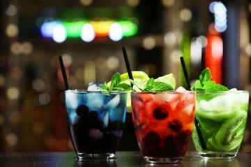 Poster - Glasses of cocktails in bar on bright blurred background