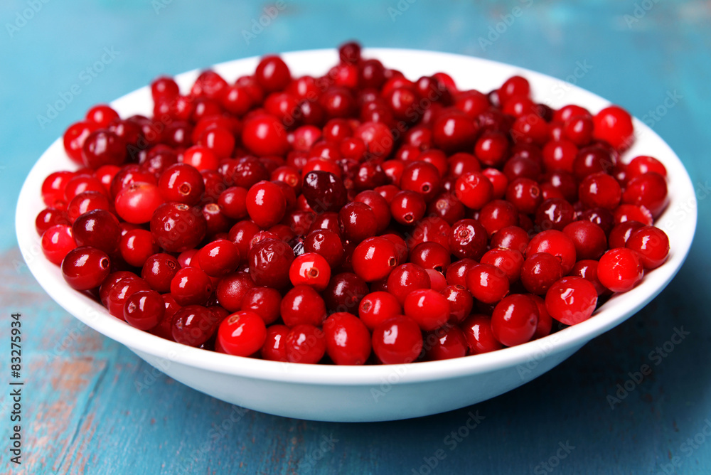Cranberries in bowl on wooden background