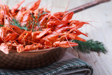 Copper frying pan with red boiled crawfish on a wooden table 