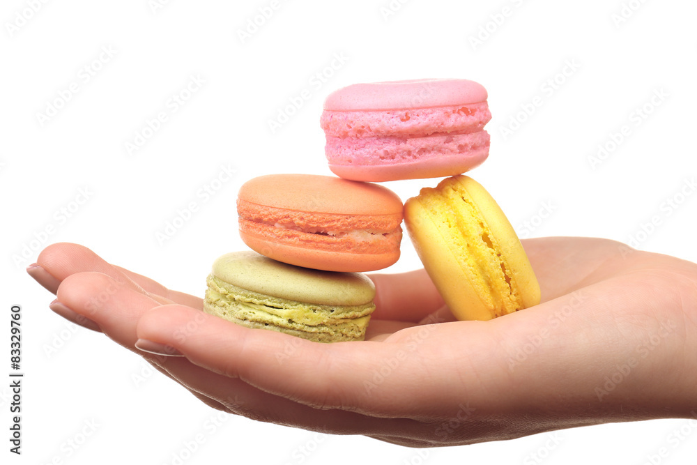 Tasty colorful macaroons in female hand isolated on white