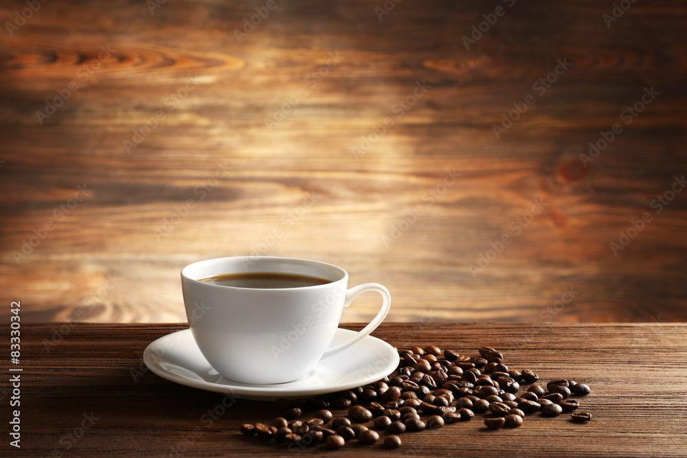 Cup of coffee with grains on wooden background