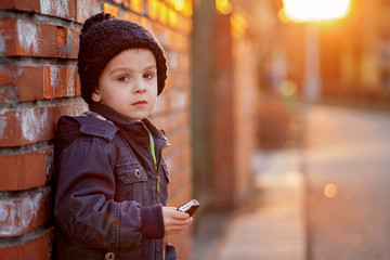 Wall Mural - Adorable little boy, next to brick wall, eating chocolate bar on