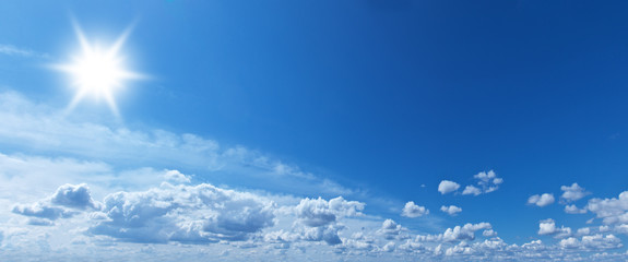 White heap clouds and bright sun in the blue sky.