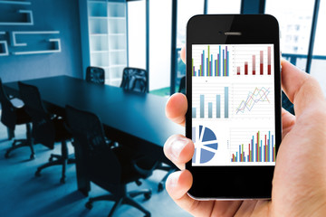 Poster - Closeup hand holding mobile phone with analyzing graph