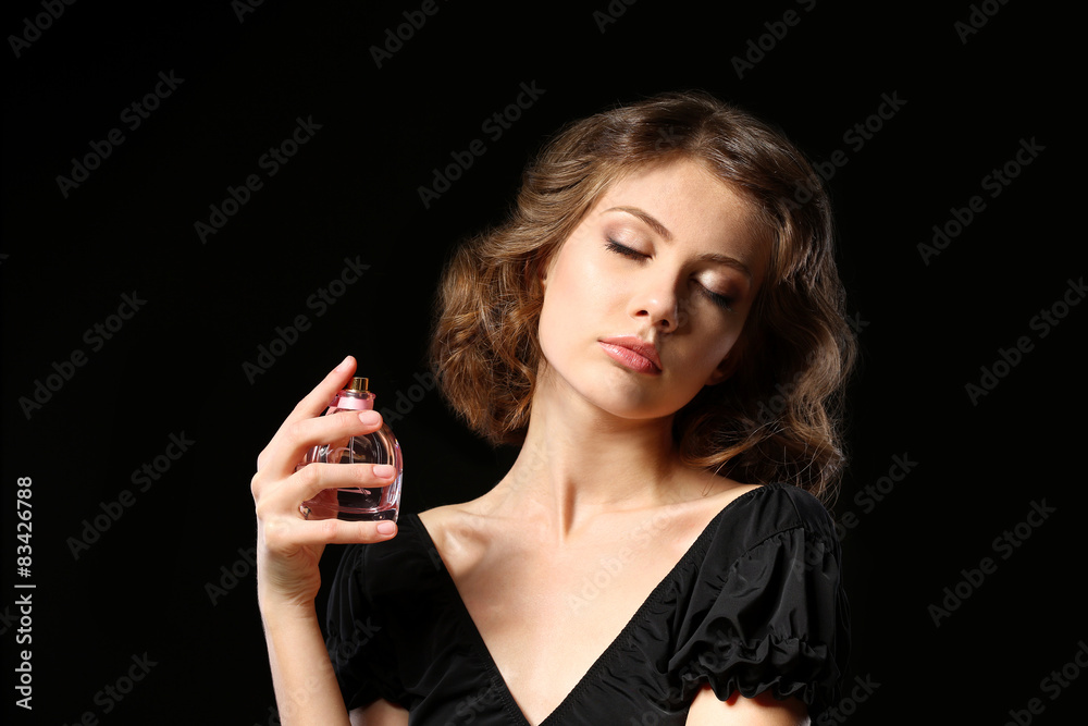 Beautiful woman with perfume bottle on black background