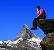 Girl sitting on a rock, in the background Matterhorn