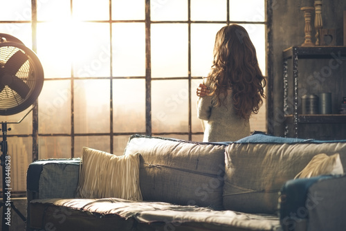 Fotografía Brunette looking out of urban loft window