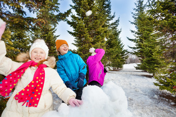 Group of happy kids throw snowballs during fight