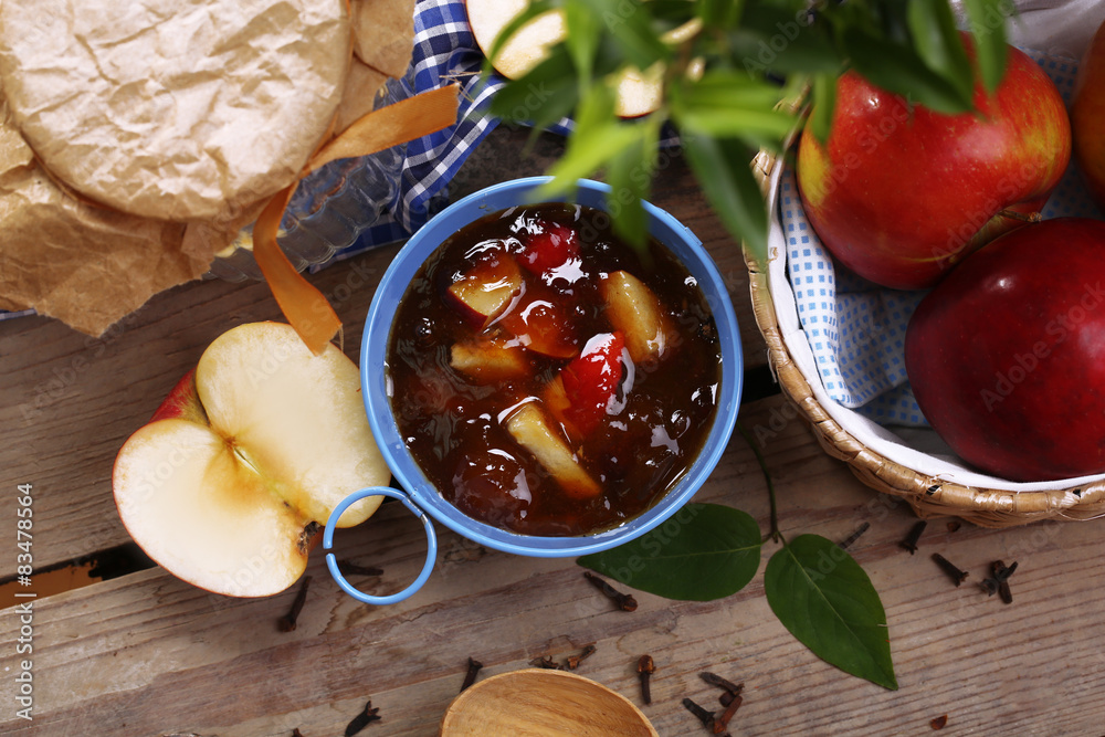 Apple jam in pail and fresh red apples on wooden table close-up