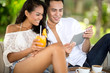 © luckybusiness - young couple in beach bar using tablet